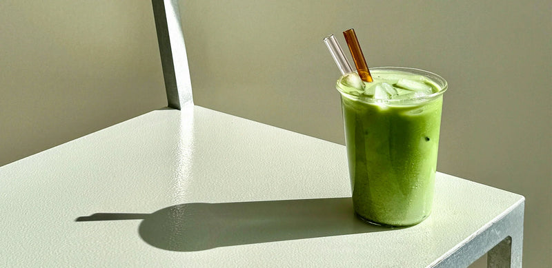  Iced green matcha latte made with KOATJI milk, placed with straws on a minimal table.