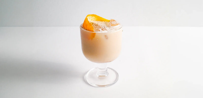 Creamy oat milk cocktail with citrus garnish in a minimalist setup, crafted with Koatji.